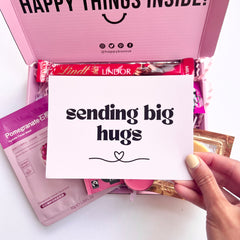 A pink greeting card saying 'sending big hugs'.