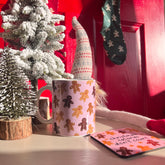 Christmas-themed mug with gingerbread design on a table with decorative items.