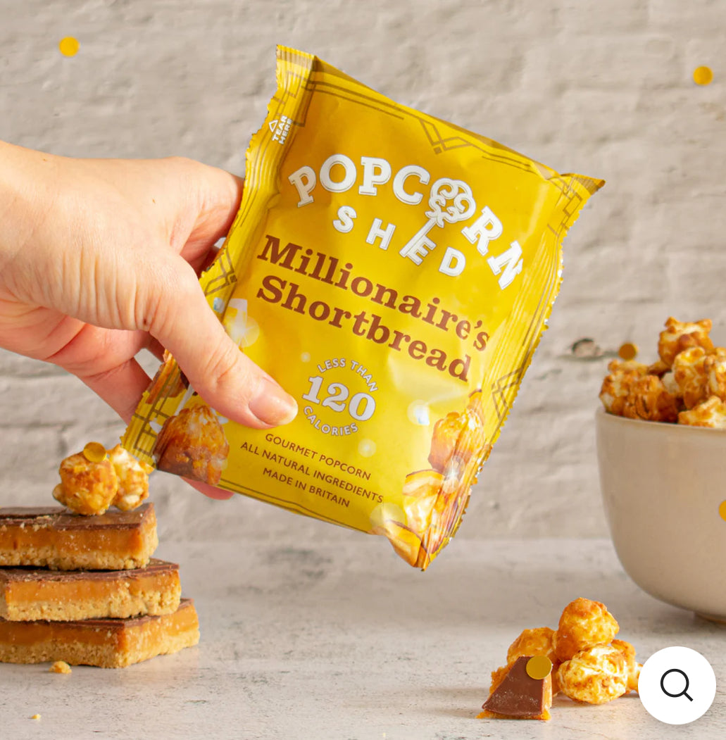 Hand holding a pack of Millionaire Shortbread popcorn.