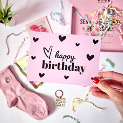 An image of the 'happy birthday' greeting card being held up by a hand and in the background you can see the gift items.