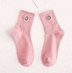 Pair of pink socks with a smiley face embroidered
