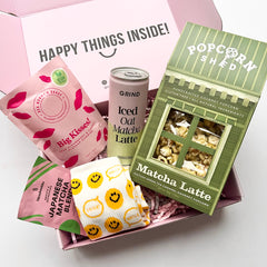 Assorted snacks including a sweets bag, Iced Oat Matcha latte can and green Popcorn box on a white background