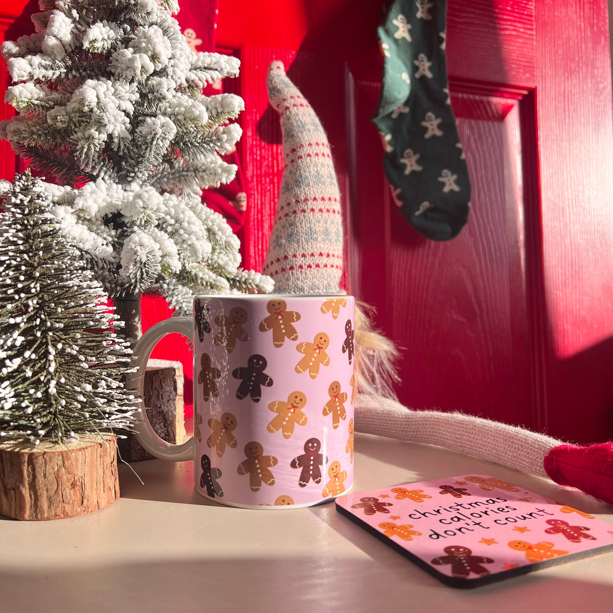 Christmas-themed mug with gingerbread design on a table with decorative items.