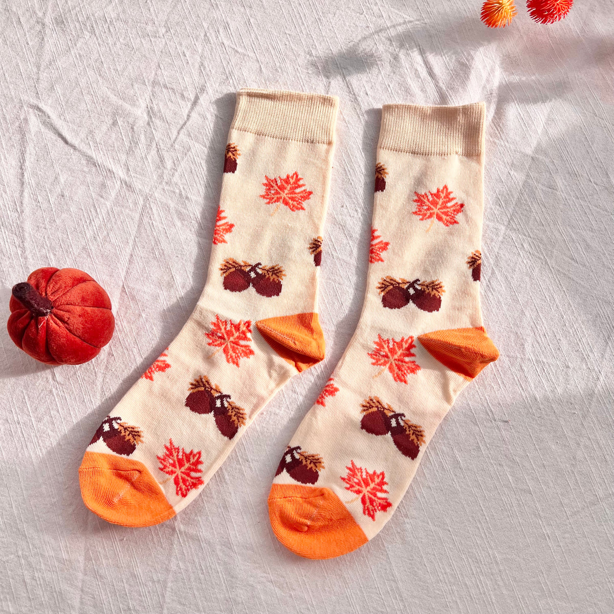 Pair of socks with autumn-themed design on a light background